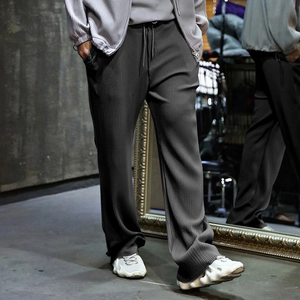 Detailed macro view of dark grey textured vertical pleated fabric on wide-leg trousers