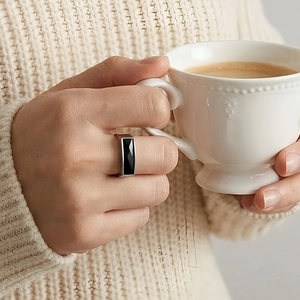 Close-up of stainless steel ring with faceted rectangular black stone on finger