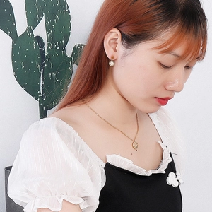 On-model view of gold geometric textured round pendant necklace and matching stud earrings