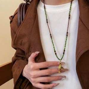Detail of beaded necklace with tiger eye stones and a textured golden pony pendant