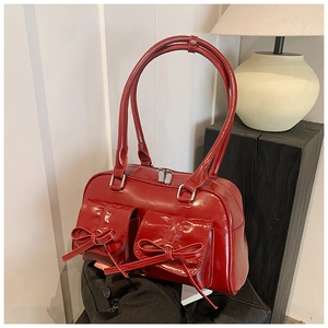 Detail of red patent leather bowling bag featuring decorative bows and glossy finish