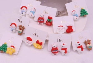 Detail shot of kids Christmas clip-on earrings featuring Santa, reindeer and tree designs