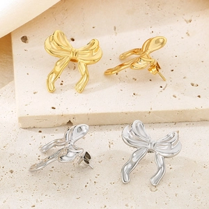 Gros plan de boucles d'oreilles papillon or et argent sur fond de pierre