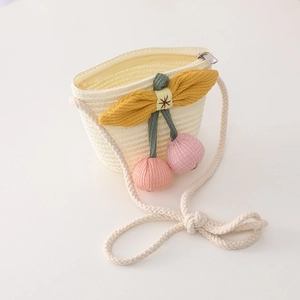 Detail of kids straw crossbody bag with yellow bow and pink cherry knitted charms