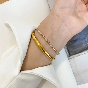 Close-up of minimalist 18K gold-plated bangle and sparkling tennis bracelet set on wrist