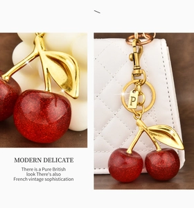 Detailed view of red cherry keychain with gold letter P charm on a quilted handbag