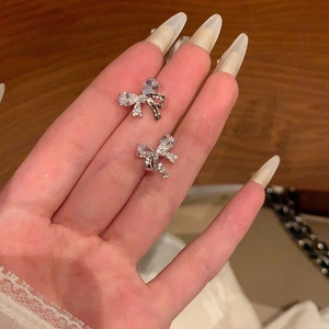 Elegant silver bow stud earrings featuring pear-cut and round-cut cubic zirconia crystals
