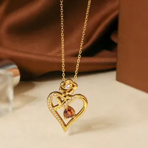 Close-up of gold titanium steel heart necklace with rose detail and zircon inlays