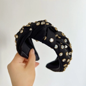 Detail of black knotted headband featuring sparkling rhinestones with gold metallic frames
