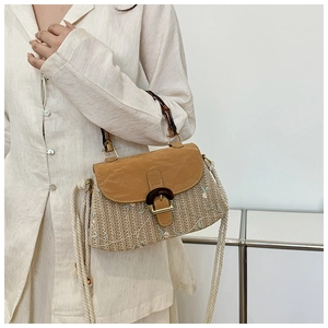 Detail of straw woven bag with floral embroidery, bamboo handle and rope strap