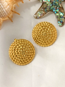 Detail of gold geometric round earrings with woven texture on a white beach setup