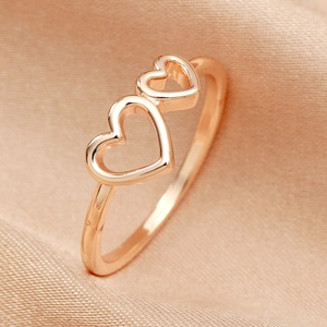 Minimalist rose gold hollow double heart ring on elegant champagne silk fabric