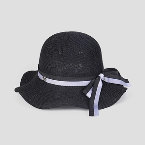Detail of black woven sun hat featuring a purple ribbon bow and gold bee charm