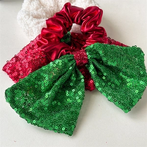 Detail of red metallic scrunchie with large green sequin bow and festive textures