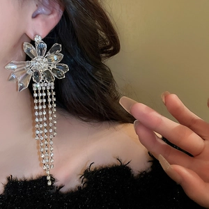 Close-up of sparkling crystal flower tassel earrings worn by a model in black plush top