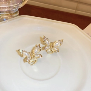 Detailed view of two small golden butterfly hair claws with pearls and colorful crystals