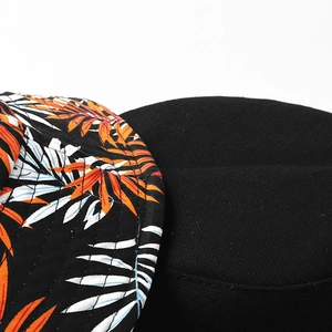Detail of leaf print bucket hat showing fabric texture and orange tropical foliage patterns