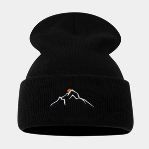 Détail de la broderie montagne au coucher du soleil sur un bonnet en maille noire d'hiver