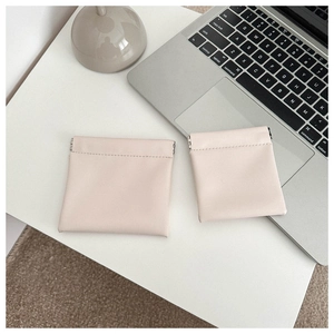 Minimalist beige PU leather coin purses in two sizes on a modern white office desk