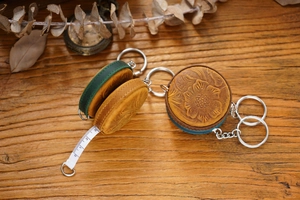 Detail of vintage embossed leather mini measuring tape with floral carving on wood
