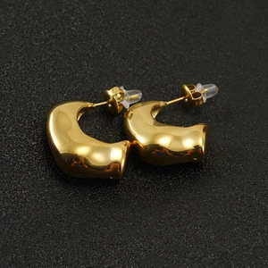 Gros plan de boucles d'oreilles en C en acier doré avec une finition polie miroir