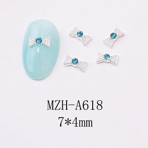 Close-up of 7x4mm silver alloy bow nail charms with blue rhinestones for manicure