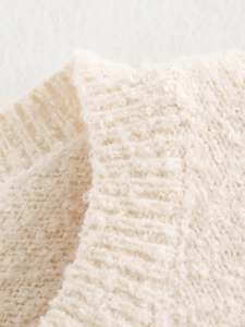 Macro shot showing the soft boucle knit texture and off-white fabric details