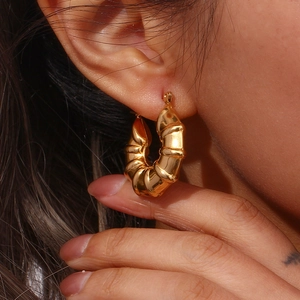 Macro shot of 18K gold hollow croissant hoop earrings worn by a model for size detail