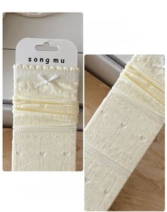 Detail of cream knit socks with hollow heart patterns and delicate white bows