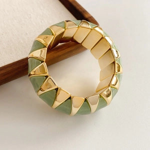 Close-up of geometric gold metal and sage green resin segments on an elastic bracelet
