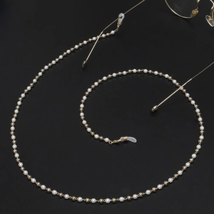 Detail of elegant white pearls and gold beads eyewear chain with silicone ends