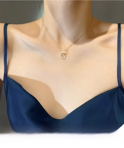 Detail of gold angel wing crown necklace with dancing stone on elegant silk model