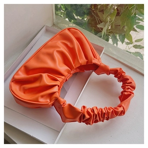 Detailed view of bright orange pleated PU cloud bag with a unique ruched handle strap