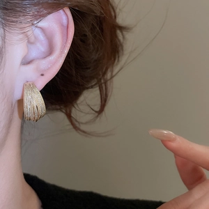 Macro shot of gold-plated multi-layer C-shape hoop earrings with textured finish