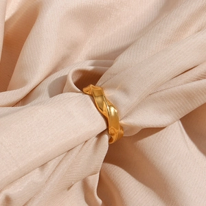 Detailed close-up of 18K gold plated stainless steel ring with twisted wave texture on silk