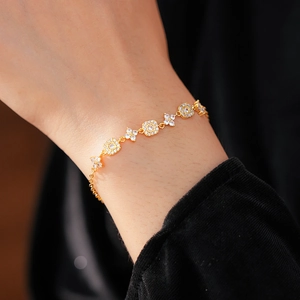 Detail of gold-plated square flower bracelet with white zircons on a woman's wrist