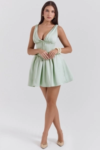 Detail of light green satin corset mini dress featuring a deep V-neck and pleated skirt