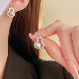 Close-up of silver gourd earrings featuring white pearls and zircon accents