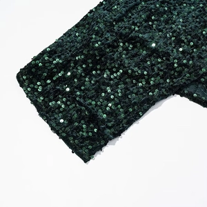 Macro shot of dark green sequins on velvet fabric showing texture and detail