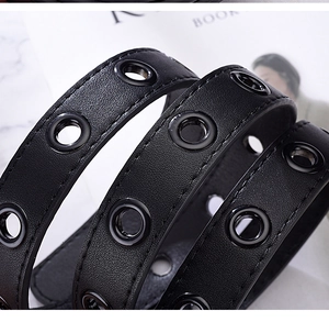 Close-up of black leather belt featuring double-row metal eyelets with grommets