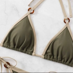 Olive green halter bikini top with amber resin rings on white marble background