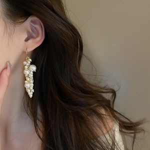 Close-up of elegant French vintage pearl tassel earrings on model with golden hooks