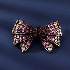 Bowknot hair clip with pink and purple rhinestones on a premium velvet background
