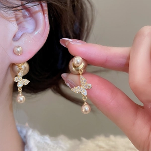 Detailed view of elegant gold butterfly pearl earrings with zircon accents on a model