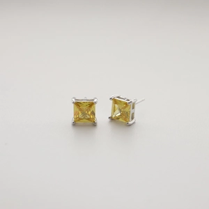 Macro shot of square-cut yellow gemstone earrings with silver claw setting and studs