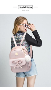 Pink PU leather backpack for women with 3D bow and fuzzy pom-pom detail on model
