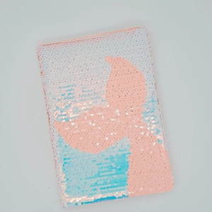 Dettaglio di paillettes reversibili sfumate rosa e blu su un taccuino creativo DIY