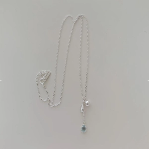 Detailed view of S925 silver necklace with light blue teardrop stone and round pendant