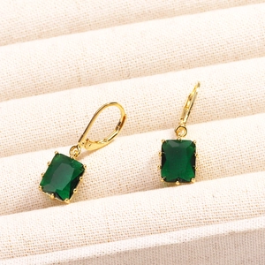 Gros plan de boucles d'oreilles plaquées or 18K avec zircons verts carrés de style émeraude