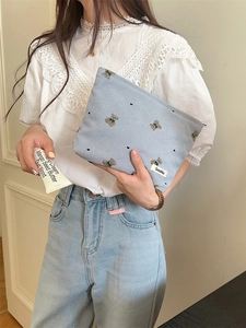 Cute blue corduroy makeup bag with embroidered bears held by a model in casual setting